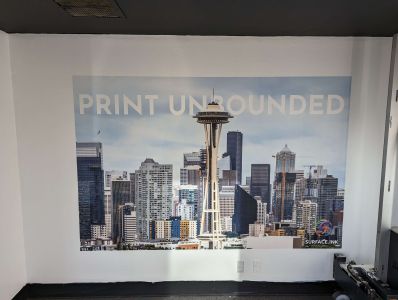 A Seattle skyline vista with the words Print Unbounded has been vertically printed on a wall