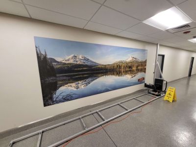 A stunning and vibrantly colorful landscape photo art canvas is on the surface of a wall with the vertical wallprinting machine on its printing track next to it