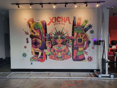 A vibrant traditional mexican print has been printed on the wall with the Surface Ink Vertical Printer moving along a track