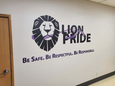 A logo of a school along with the words be safe and respectful has been printed on a school wall in vibrant detail using the CMYK wallprinter