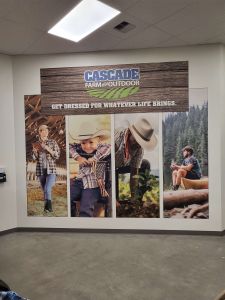 A giant print featuring Cascade Farm and Outdoor store branding with pictures of coboys, kids, outdoor enthusiasts in Oregon and the Pacific Northwest has been printed on a wall